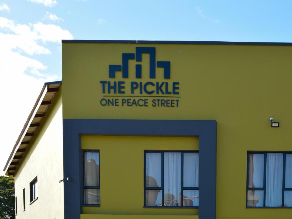 un edificio amarillo y verde con un pepinillo en una calle de paz en The Pickle Residence, en Tzaneen