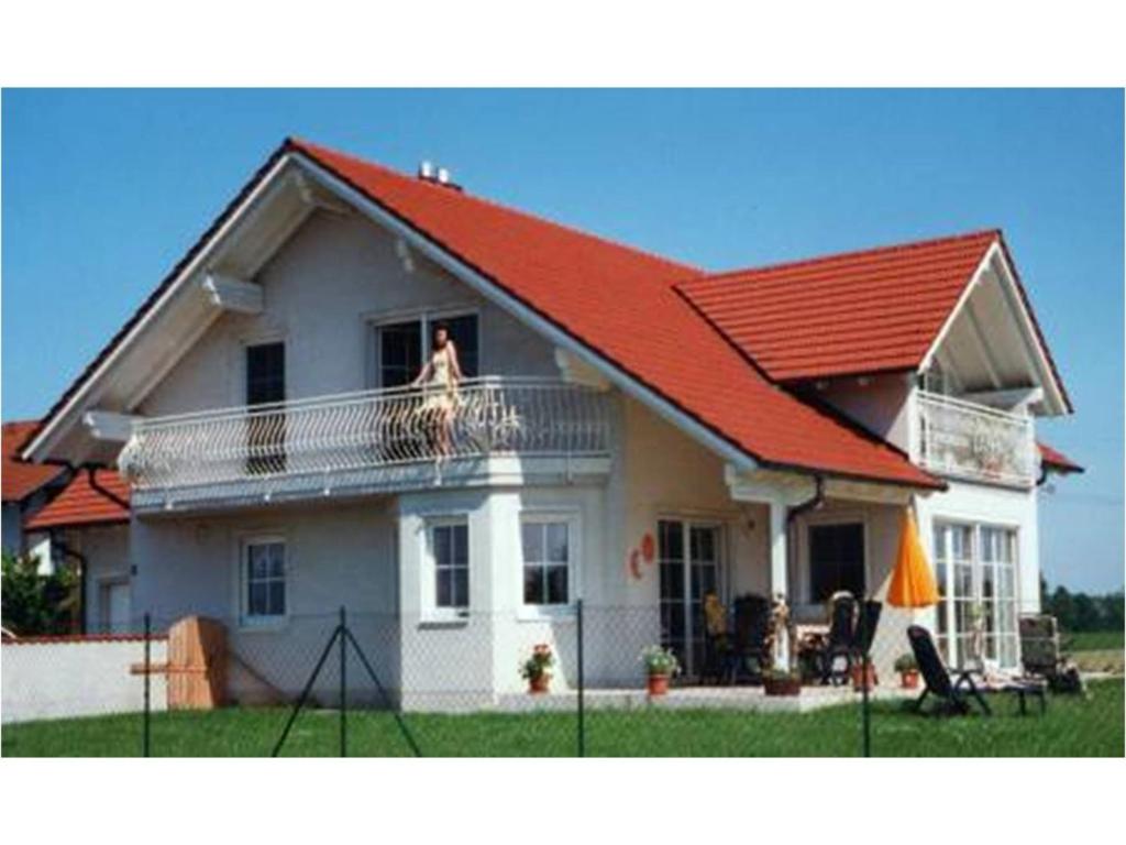 ein Haus mit rotem Dach mit einem Hund auf dem Balkon in der Unterkunft Appartement Haus Anja in Bad Füssing