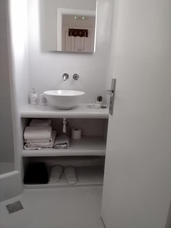 a white bathroom with a sink and a mirror at Studios Irineos in Perissa
