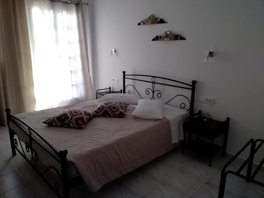 a bedroom with a bed with white sheets and a window at Studios Irineos in Perissa
