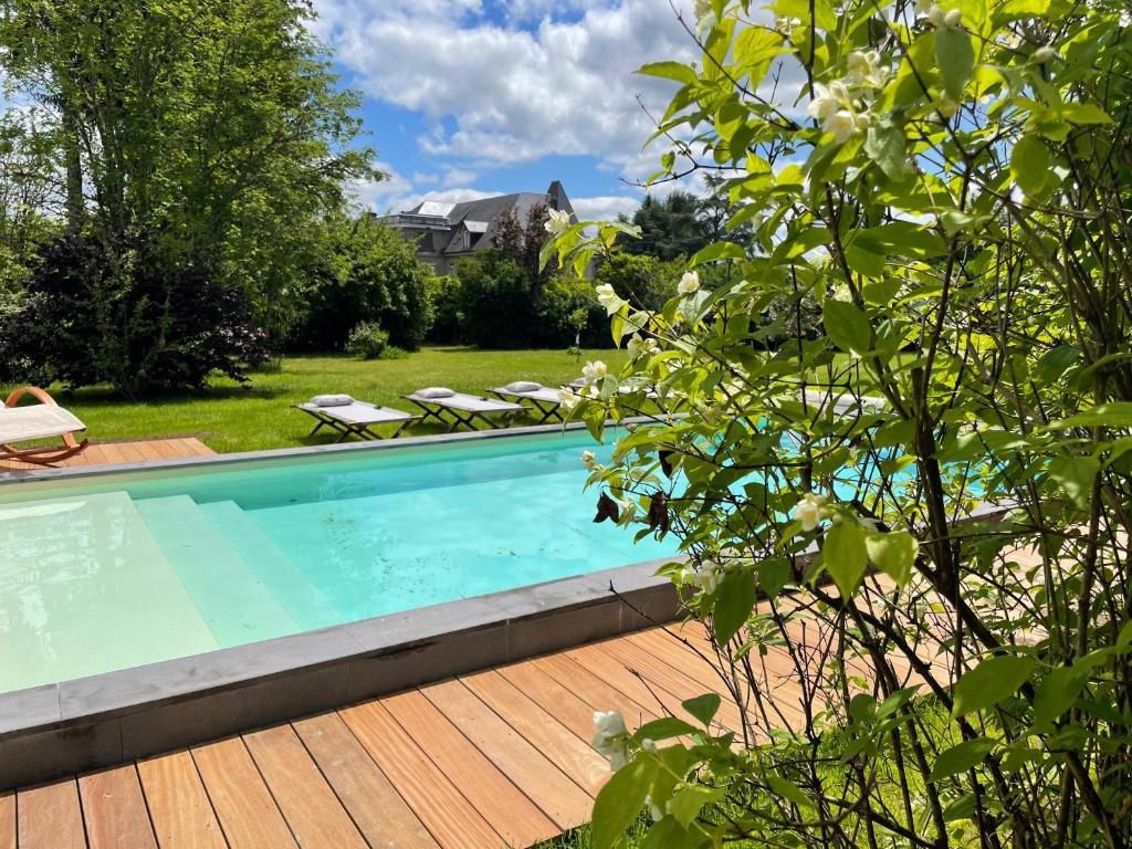 una piscina en un patio con terraza de madera en VILLA MURA gite luxe avec piscine et spa campagne et grand air nouvelle Aquitaine Corrèze, en Neuvic