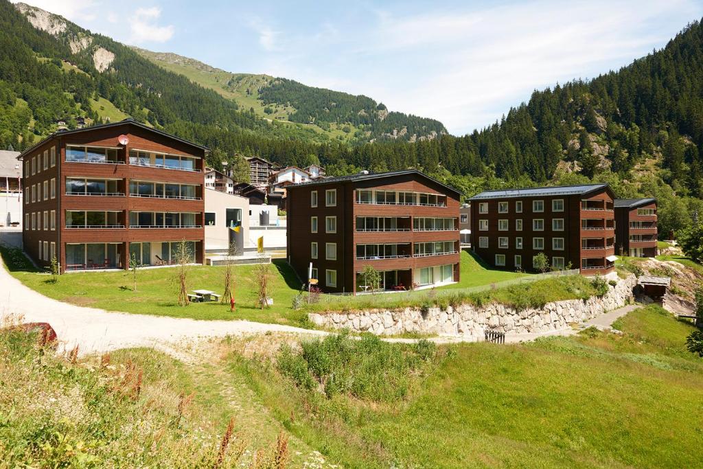 a group of buildings on a hill with mountains in the background at Reka-Feriendorf Blatten-Belalp in Blatten bei Naters