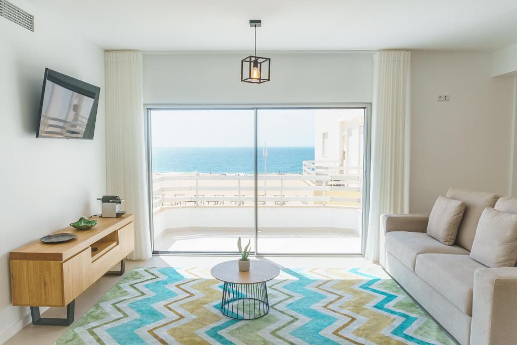 a living room with a couch and a view of the ocean at Marisol Mar in Nazaré