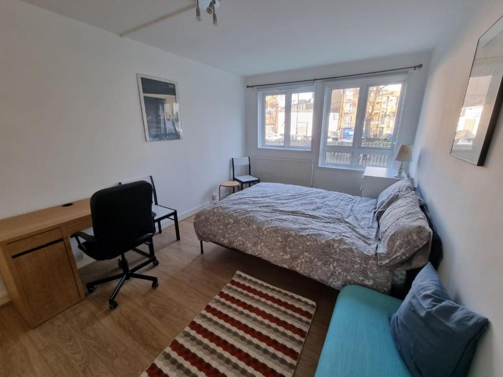 um quarto com uma cama, uma secretária e uma cadeira em 2 Bedroom Apartment in Kentish Town em Londres