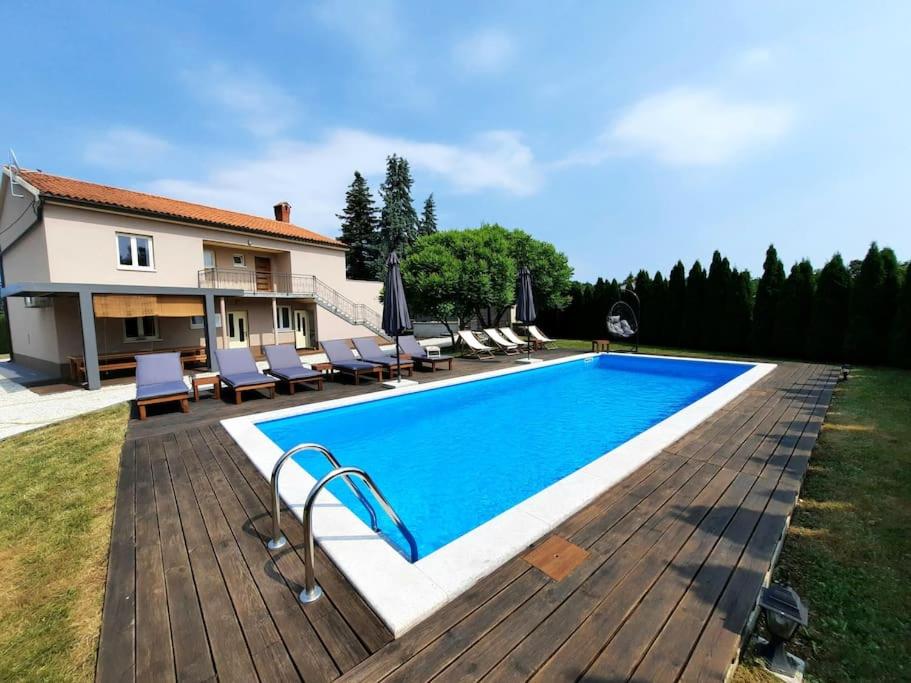 a swimming pool with chairs and a house at Large apartment in Central Istria with private pool in Pulići