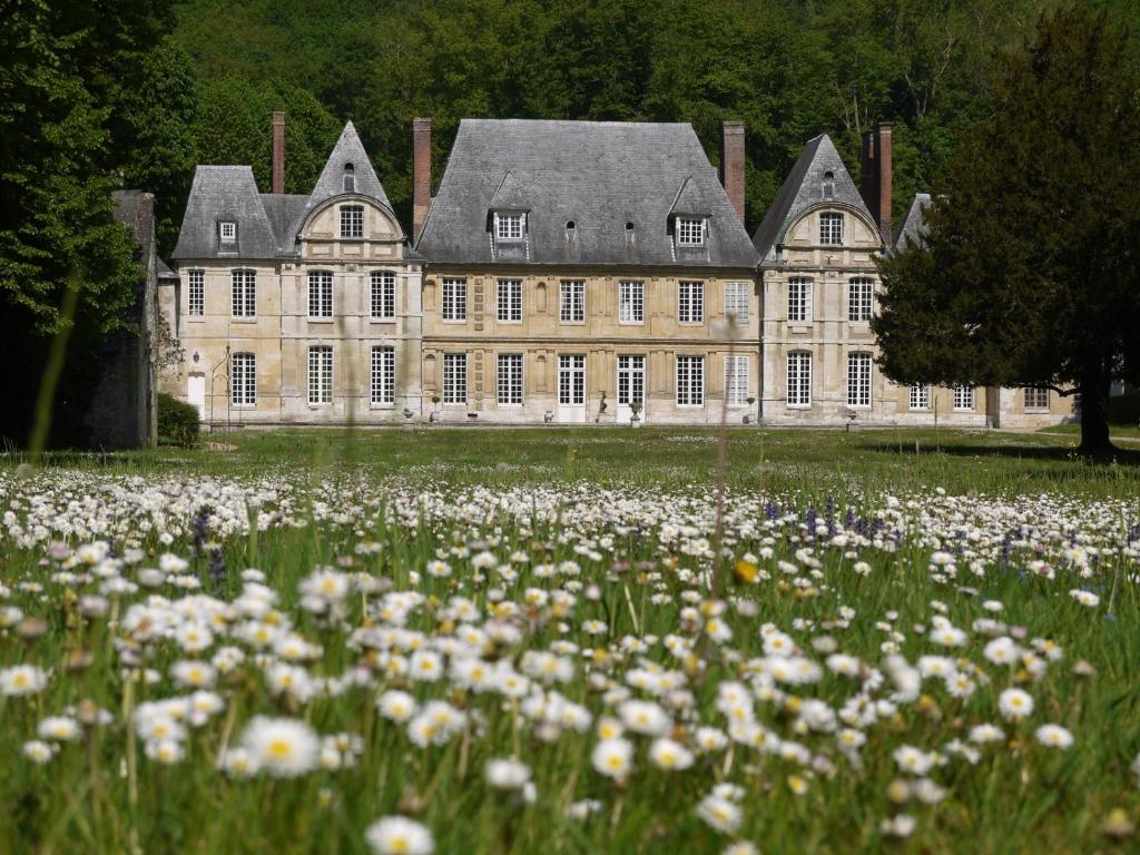 um grande edifício com um campo de flores em frente em Maison du Chapelain em Duclair