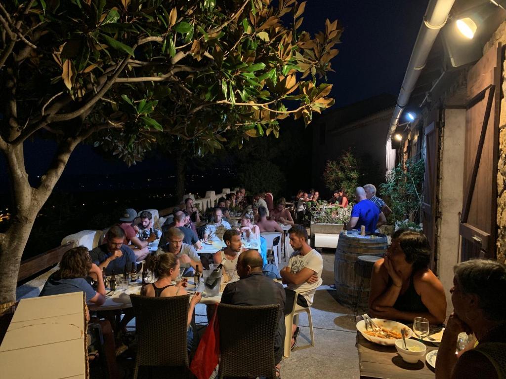 un grupo de personas sentadas en mesas en un patio por la noche en Relais International de la Jeunesse en Calvi