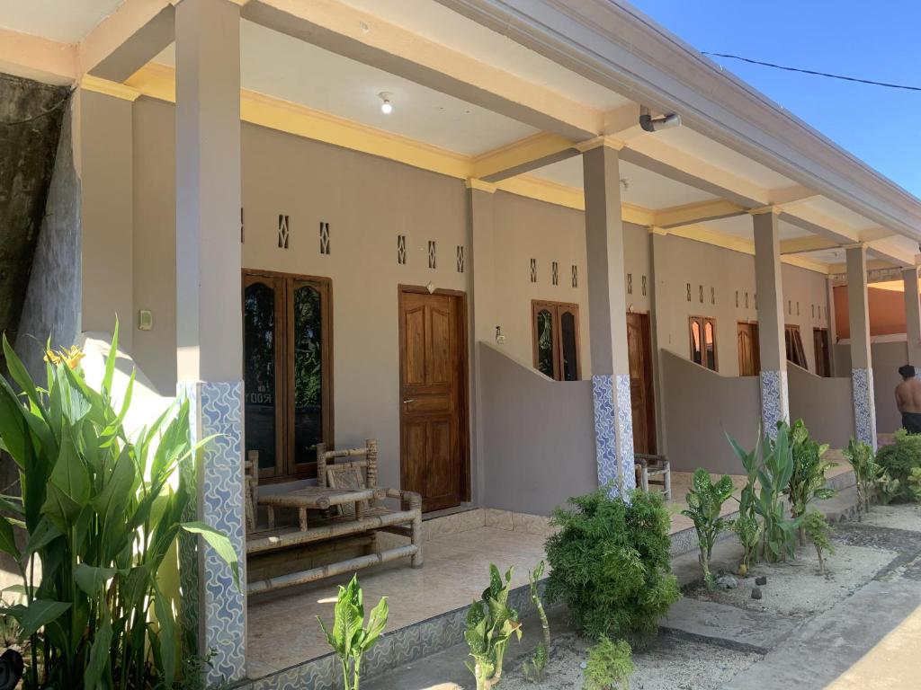 eine Reihe von Häusern mit Holztüren und Pflanzen in der Unterkunft Roby Homestay in Kuta Lombok