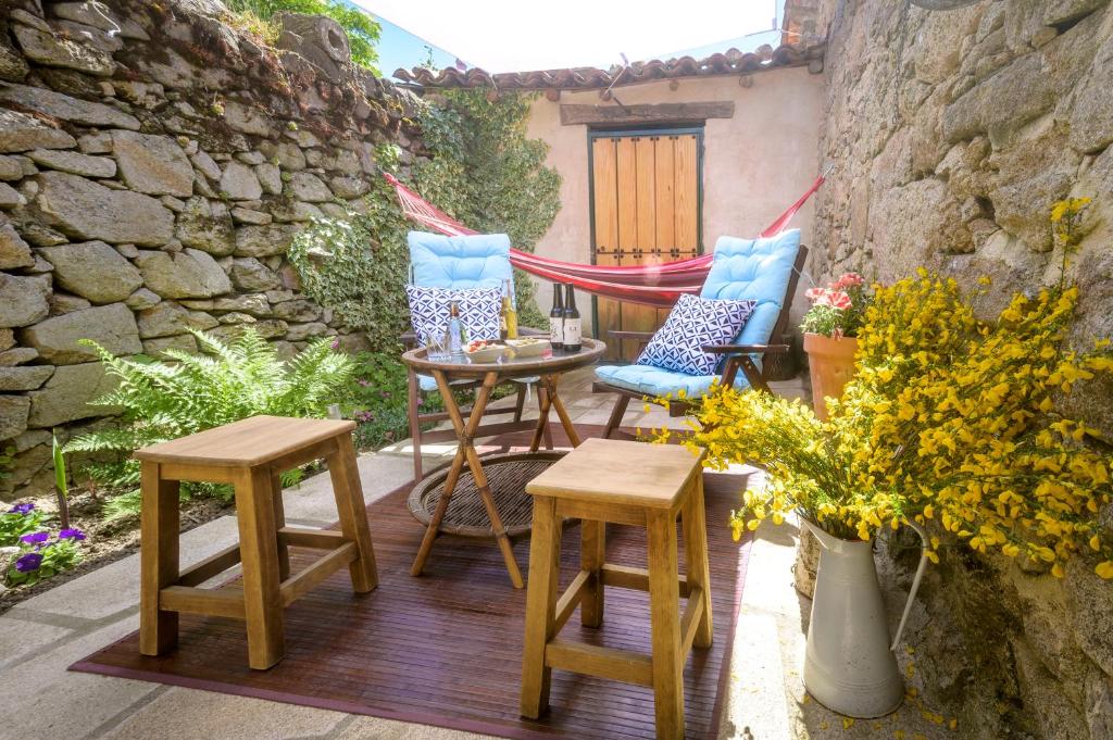 un patio con 2 sillas, una mesa y 2 taburetes en El Colirrojo - Los Sitios de Aravalle, en Casas del Abad