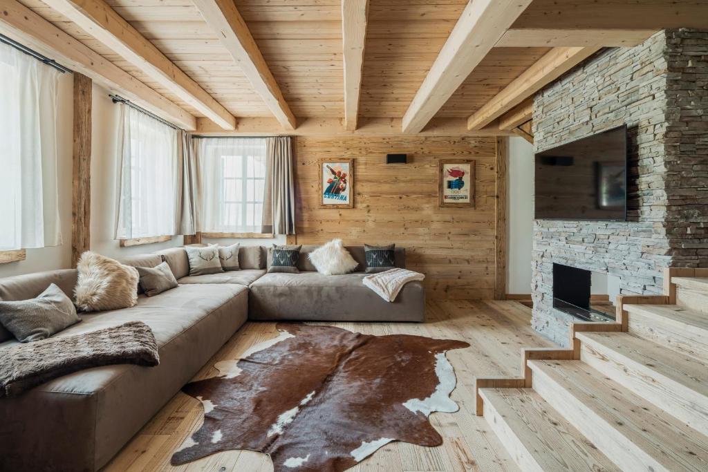 a living room with a couch and a stone fireplace at Chalet Socrepes - Dolomiti Skyline in Cortina dʼAmpezzo