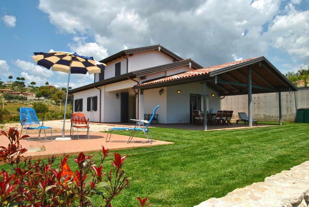 a house with a patio with chairs and an umbrella at RED ROSES appartamento al piano terra in villa in Itri