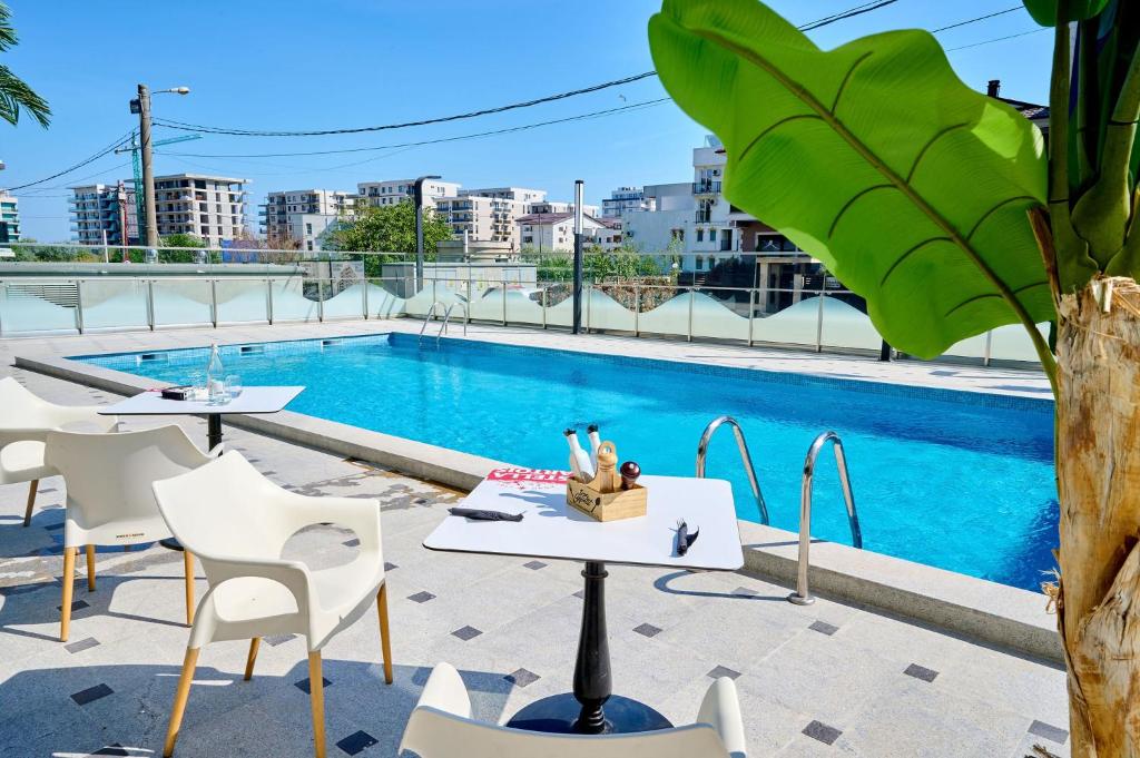 a patio with tables and chairs next to a swimming pool at Color Studios in Nord10 - Pool & playground in Mamaia