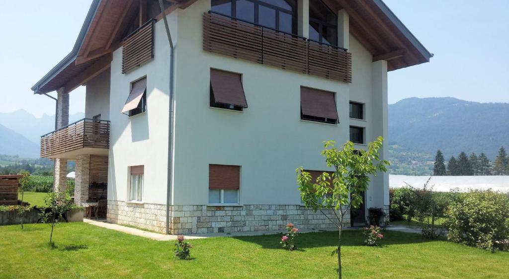 a white building with a balcony and a grass yard at Casa Vacanze Hartriegel in Comano Terme