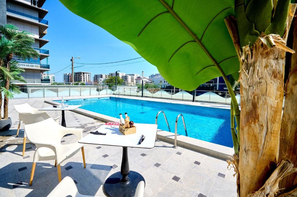 - une table et des chaises à côté de la piscine dans l'établissement Turquoise Apartment Nord10 - Pool n Parking, à Mamaia