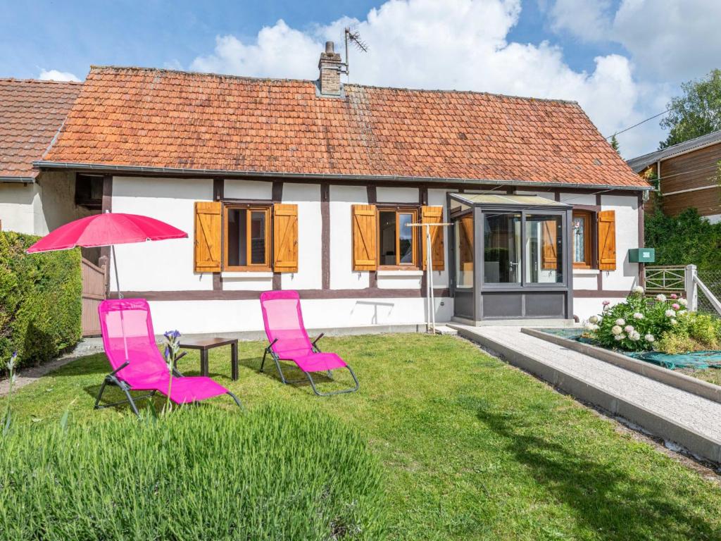 ein Haus mit zwei rosa Stühlen und einem Tisch mit einem Sonnenschirm in der Unterkunft Holiday Home La Mesnièroise - MEB400 by Interhome in Mesnières-en-Bray