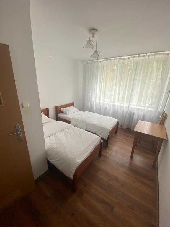 a room with two beds and a table and a window at Leśna Polana in Sękocin Stary