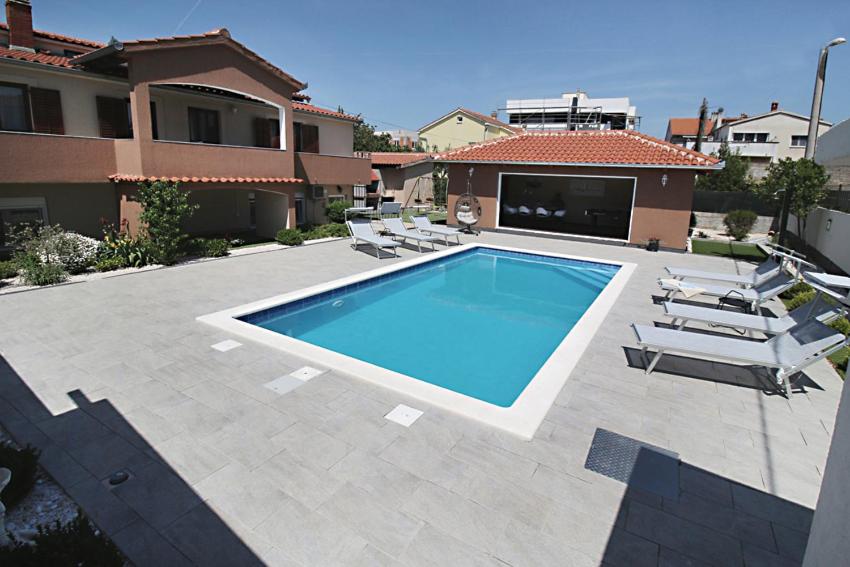 a swimming pool with lounge chairs and a house at Vila Anda in Zadar