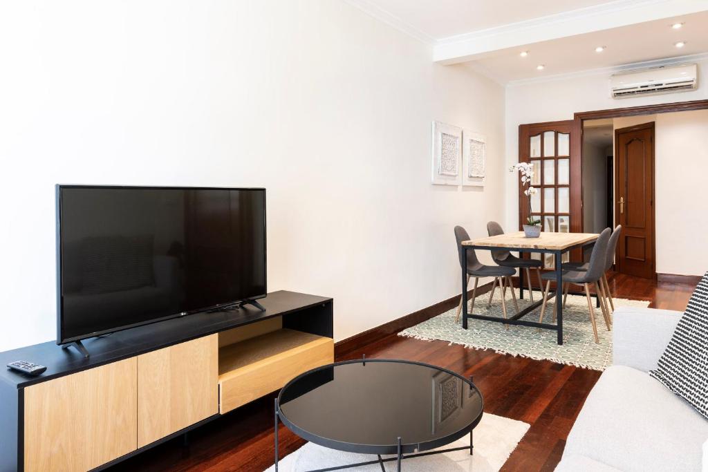 ein Wohnzimmer mit einem TV und einem Tisch in der Unterkunft Beach and Chill apartment by Cisan Rentals in San Sebastián