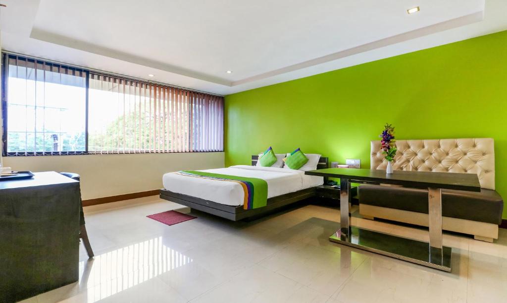 Dormitorio verde con cama y mesa en Treebo Trend Concerto Residentia, en Durgāpur
