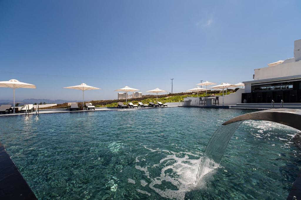 a swimming pool with a fountain in front of a building at Cape Sisu Suites in Akrotiri