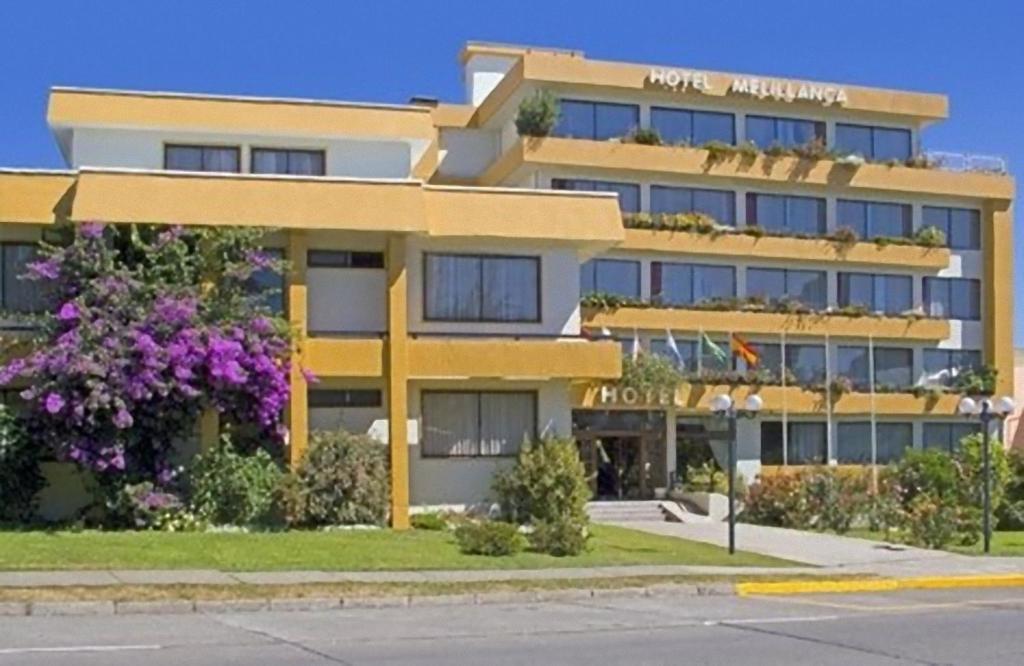un gran edificio amarillo en el lateral de una calle en Hotel Melillanca, en Valdivia