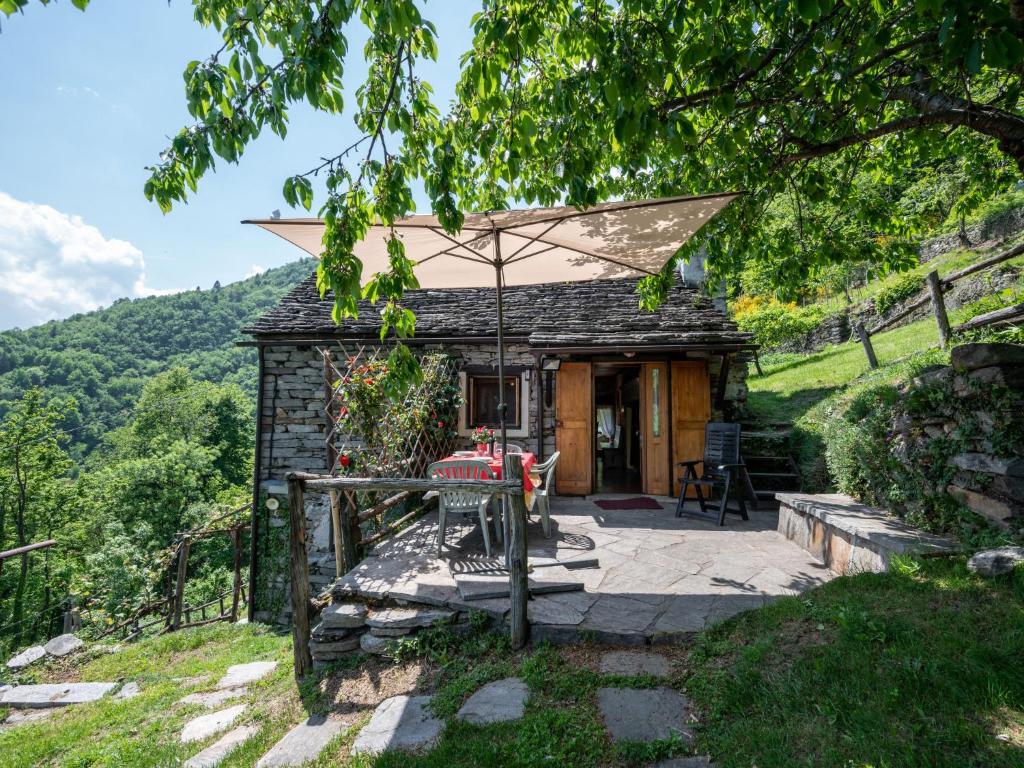 a stone cottage with an umbrella and a patio at Chalet Baita Degli Orsi - DOD110 by Interhome in Murata