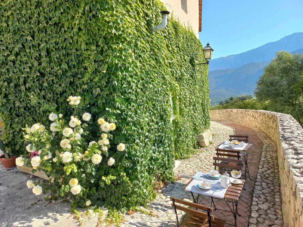 a table and chairs in front of a hedge with flowers at L'armonica di nonnoSandro in Corfinio
