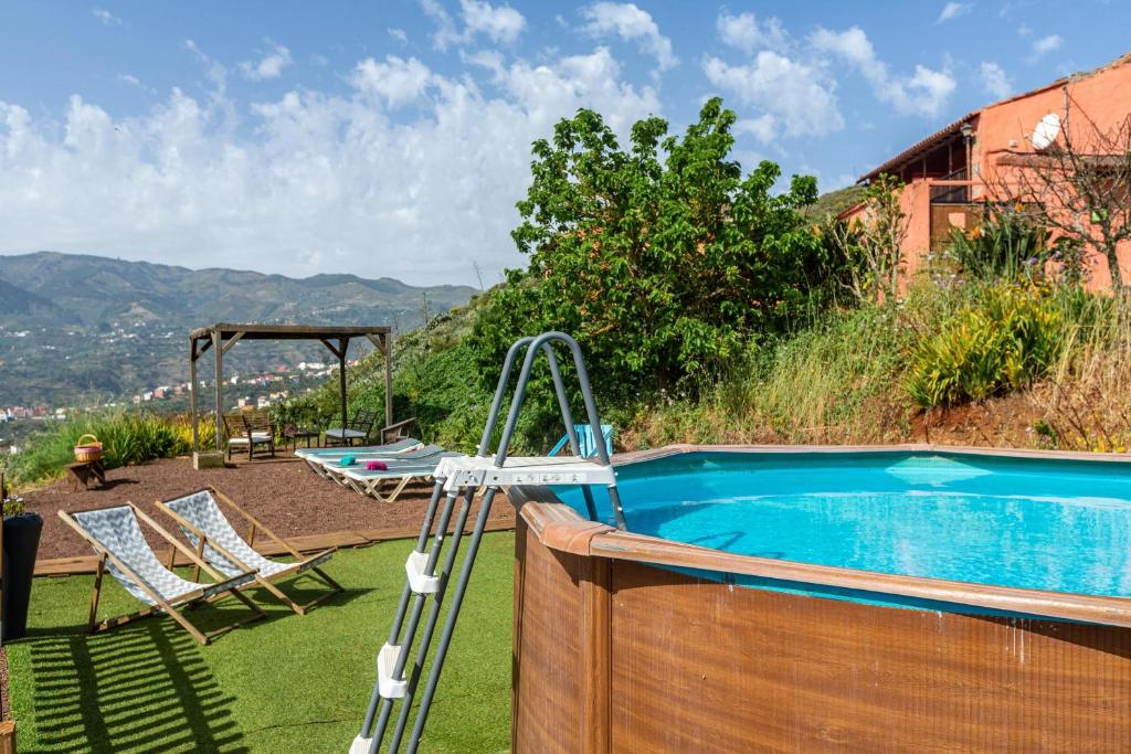 una piscina con 2 sillas y un columpio en Casa Rural La Caldera en Teror