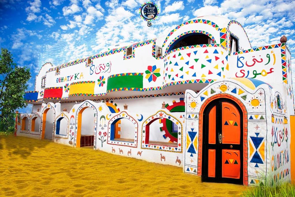 Onaty Ka Guest House في أسوان: مبنى كبير ذو تصاميم ملونة من جانبه