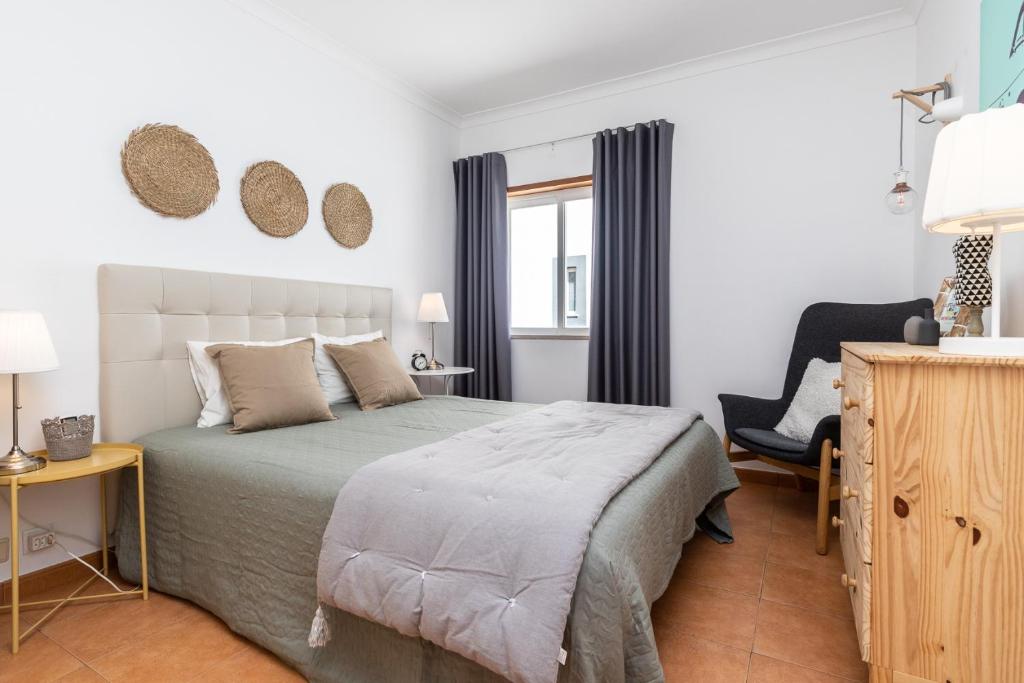 ein Schlafzimmer mit einem Bett, einem Stuhl und einem Fenster in der Unterkunft Cabanas Green Apartment & Loft. in Cabanas de Tavira