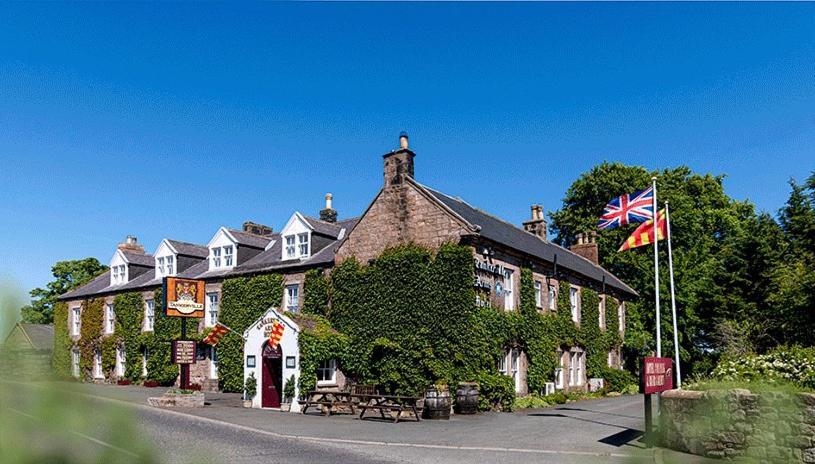 un edificio con una bandera delante de él en Tankerville Arms Hotel, en Wooler