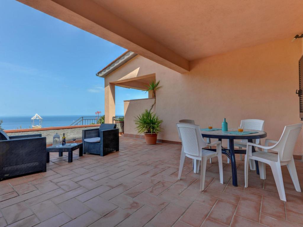 un patio con tavolo, sedie e vista sull'oceano di Apartment La Paradisa-2 by Interhome a Nisporto