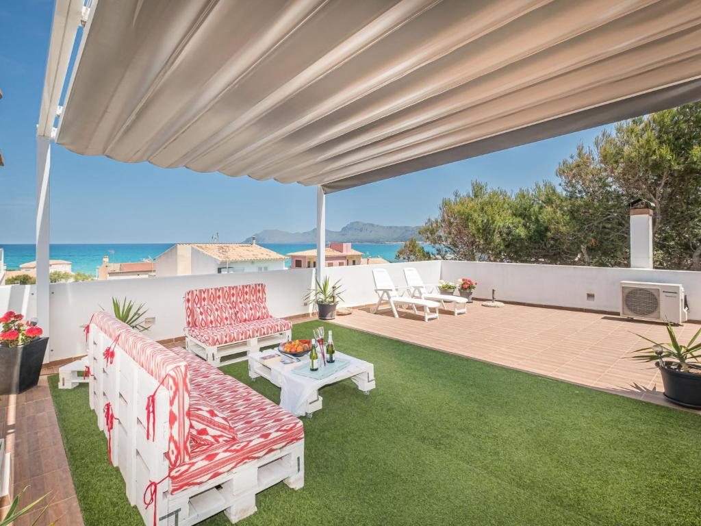 un patio con muebles rojos y blancos y el océano en Apartment Misefo - PIC275 by Interhome, en Son Serra de Marina