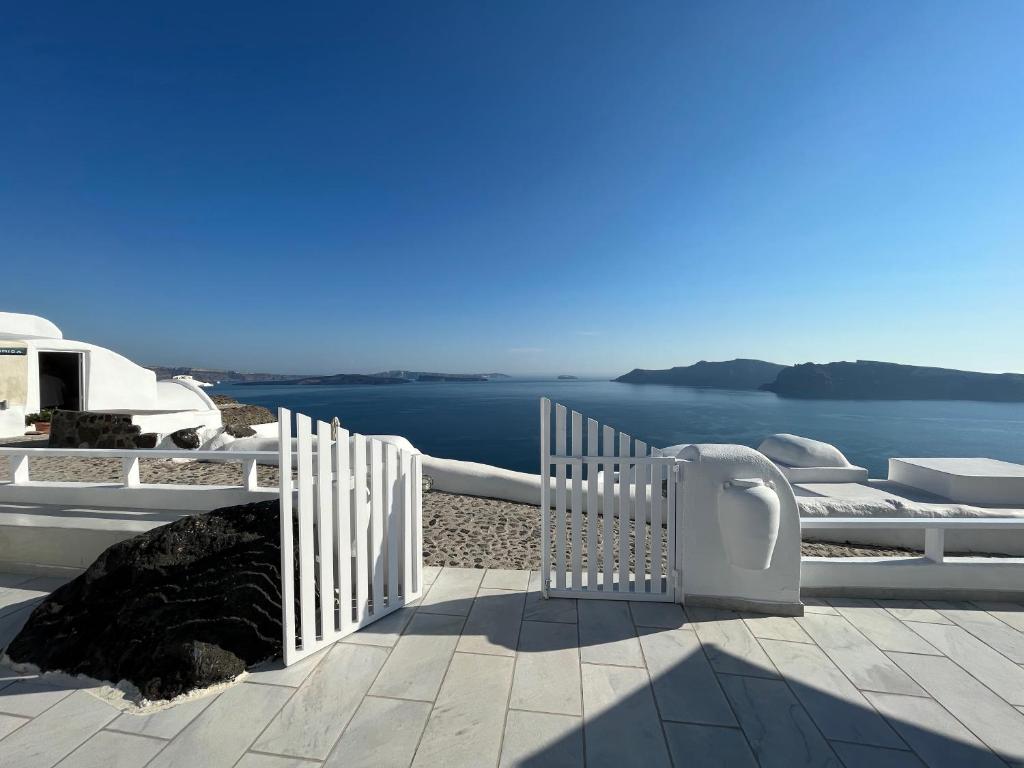 a white fence with a view of the water at Olympic Villas in Oia