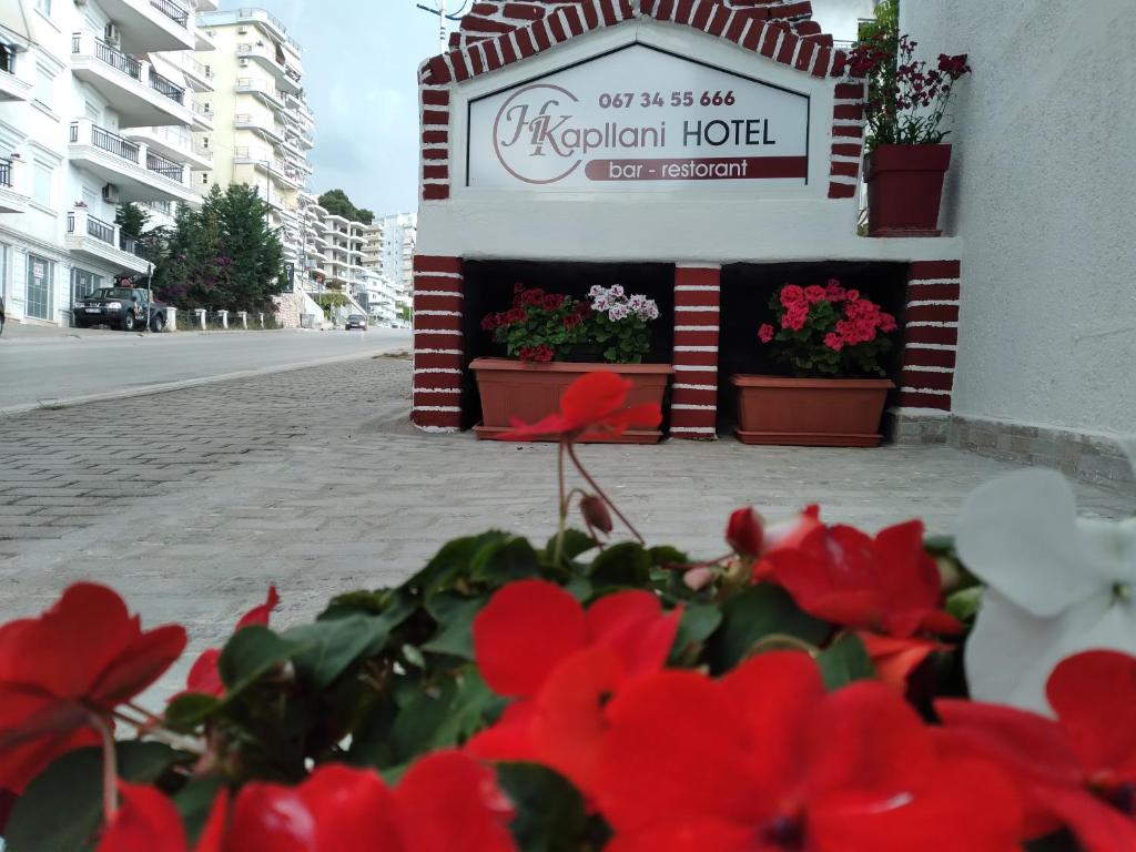 a hotel sign with red flowers in front of it at Hotel Vila Kapllani in Sarandë