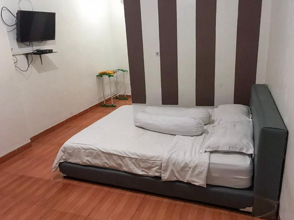 Bett in einem Zimmer mit gestreifter Wand in der Unterkunft KoolKost @ Tarahan Lampung (Minimum Stay 30 Nights) in Blimbing