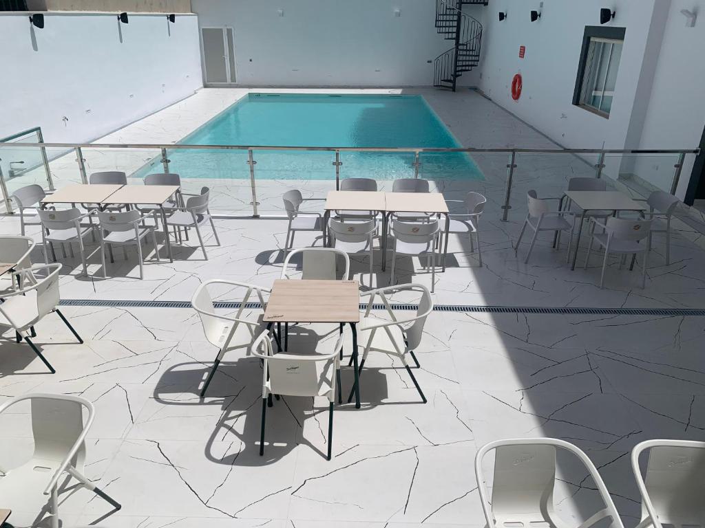 a pool with tables and chairs next to a swimming pool at Hostal La Paz in Ossa de Montiel