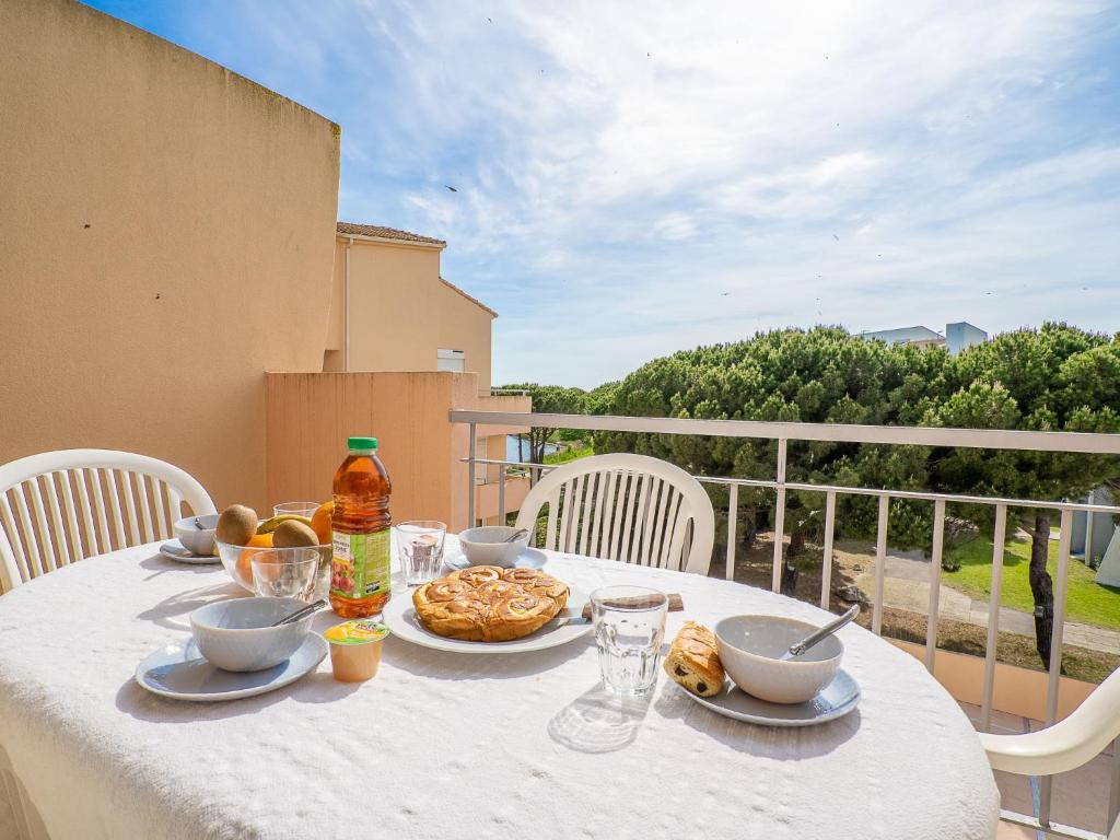 einen weißen Tisch mit Speisen und Getränken auf dem Balkon in der Unterkunft Apartment Les Rives du Lac-7 by Interhome in Le Grau-du-Roi