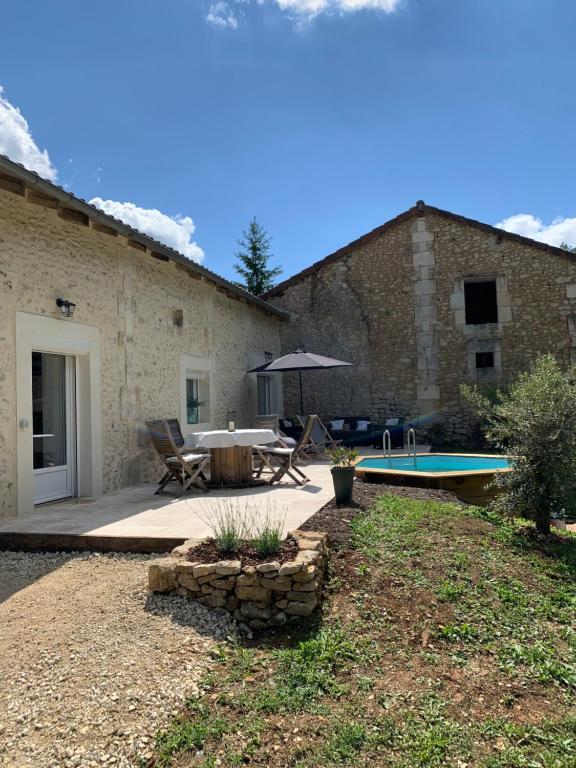 un patio con una mesa y una sombrilla junto a un edificio en Maison de famille 24 en Trélissac