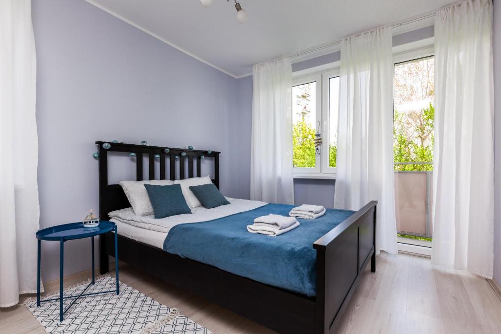 een slaapkamer met een bed met blauwe lakens en ramen bij Prime Home PARKOWY in Gdynia