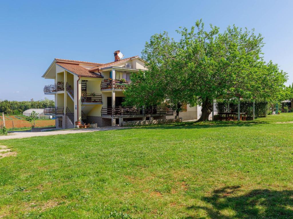 a house with a tree in front of a yard at Apartment Vesela-4 by Interhome in Savudrija
