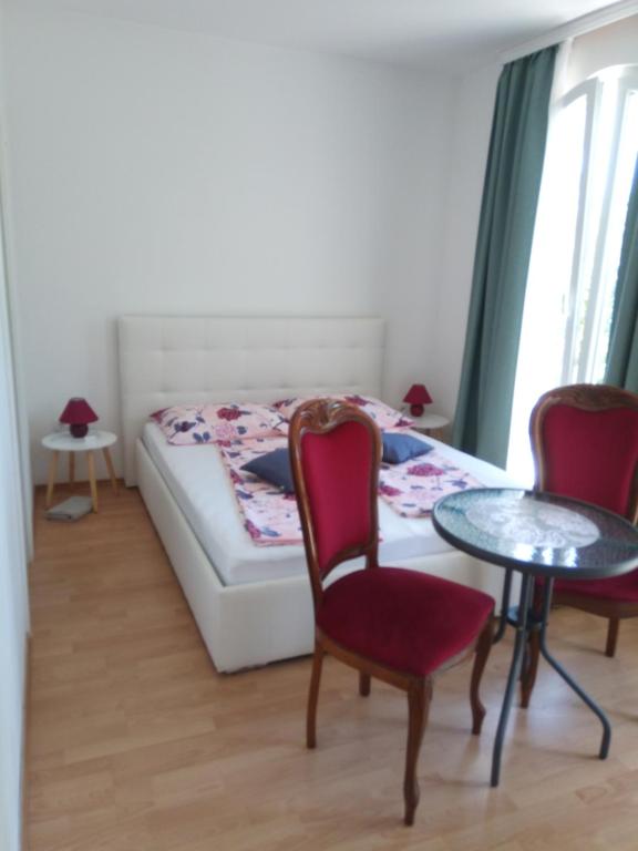 a bedroom with a bed and two chairs and a table at Ana Rooms in Krk