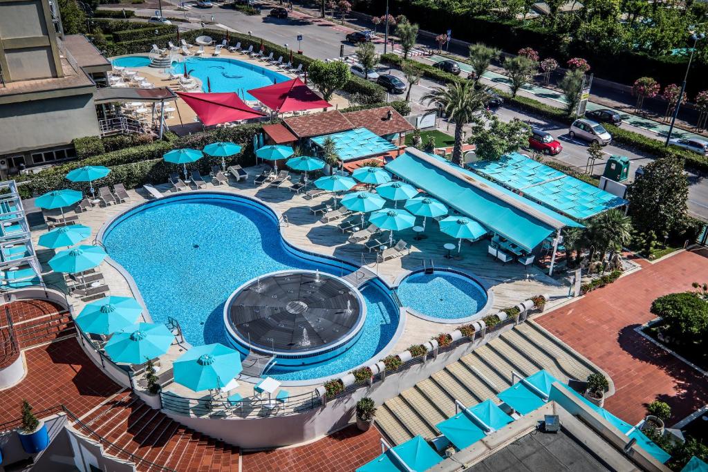 an overhead view of a swimming pool with blue umbrellas at B&B Hotel Chioggia Airone in Sottomarina