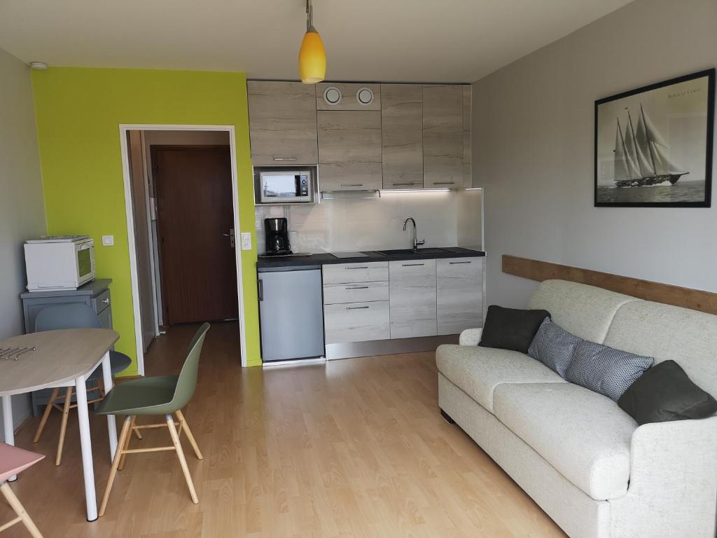 Una sala de estar con un sofá y una cocina. en Le Sylvania, en Saint-Georges-de-Didonne