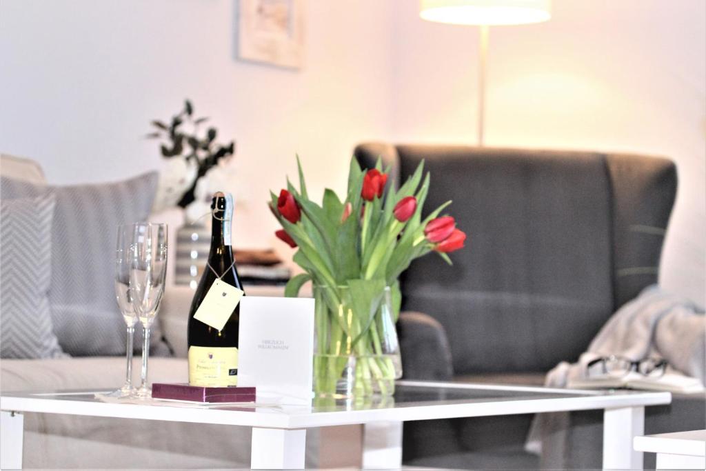 a table with a vase of flowers and a bottle of wine at KranichSuite - Zingst in Zingst