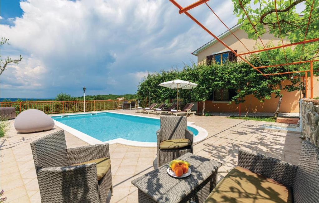 a pool with chairs and a table with a bowl of fruit at 7 Bedroom Nice Home In Labin in Labin