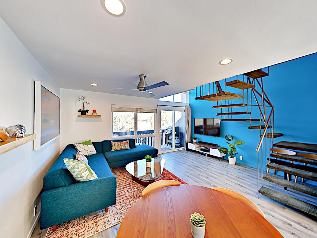 a living room with a blue couch and a spiral staircase at Hale I'a in Carpinteria