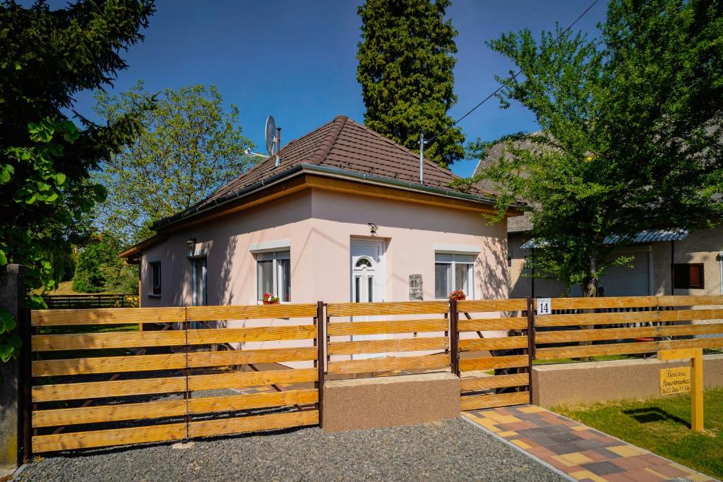 uma casa com uma cerca de madeira em frente em Bodza Apartmanház em Harkány