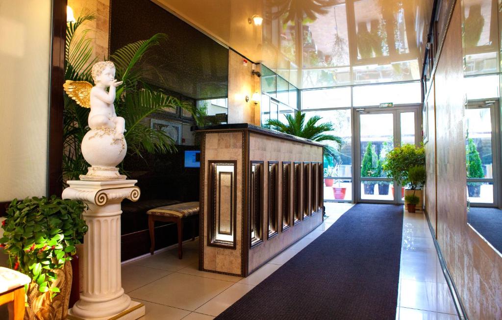a lobby with a statue and plants in a building at Afina Hotel in Adler