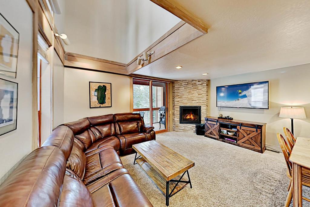 een woonkamer met een leren bank en een open haard bij Gold Bend Adventure in Truckee